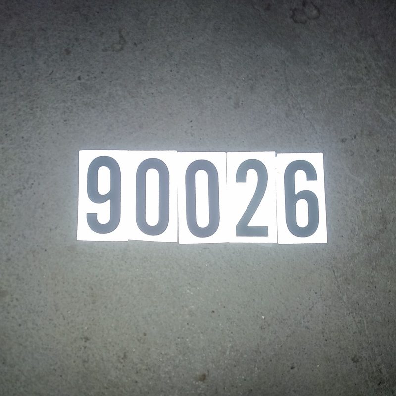 Stick-on vinyl numbers reading 90026 on concrete ground